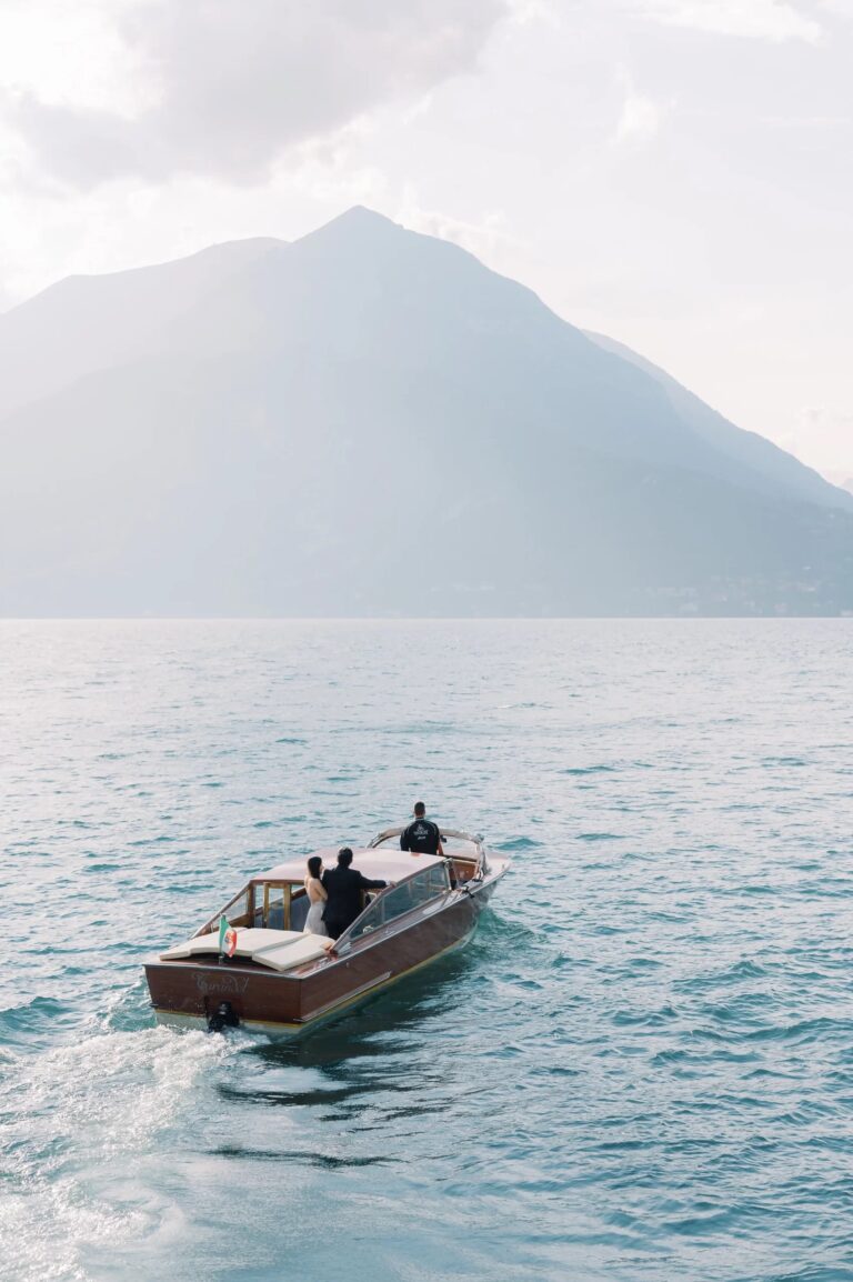 The couple's boat crossing Lake Como beneath the mountains, Rocco Daniele Photography