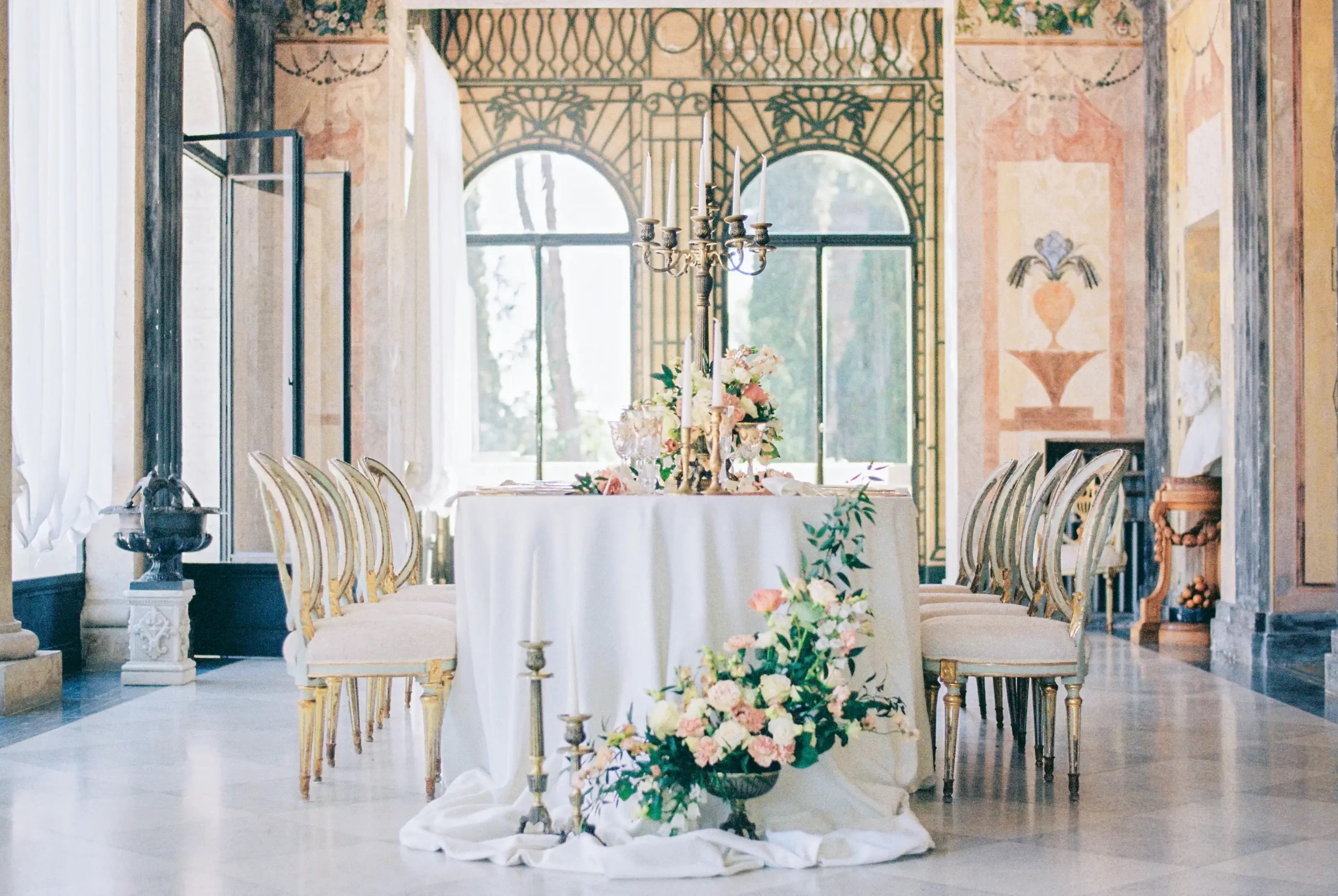 The frescoed hall set for dinner, with flowers and gilded chairs, Torre di Pila, Umbria, Rocco Daniele Photography