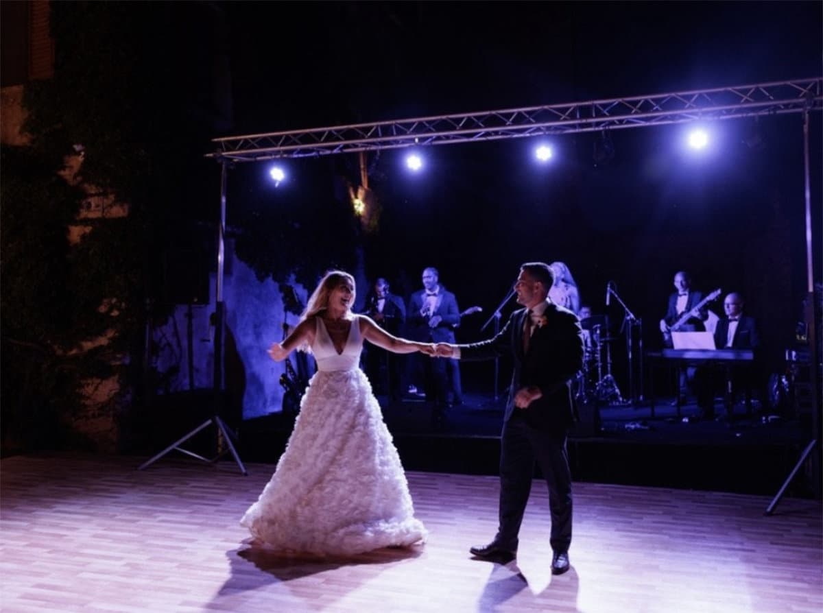 A couple dancing in front of the band on a lit stage