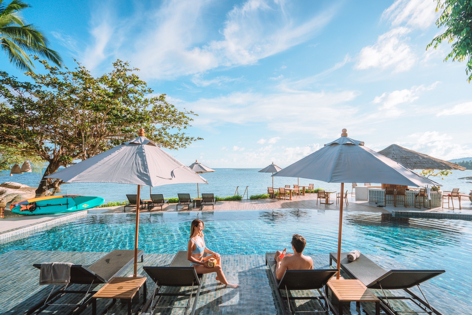 Guests on sun loungers beside the pool with the sea beyond, Rocky’s Boutique Resort