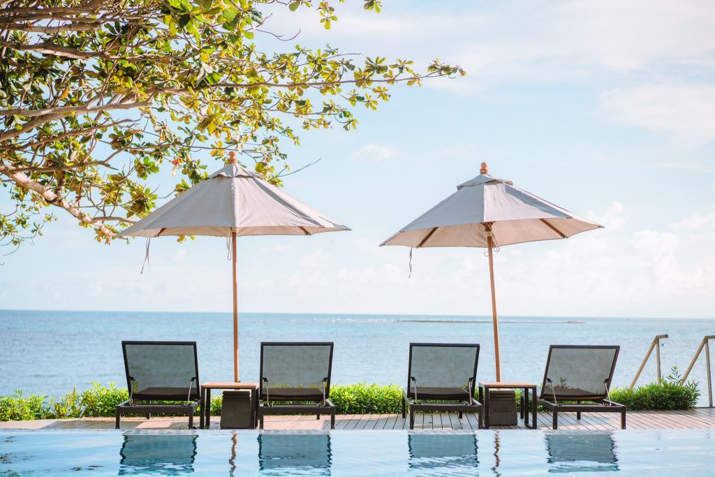 Sun loungers and parasols at the edge of the pool facing the sea