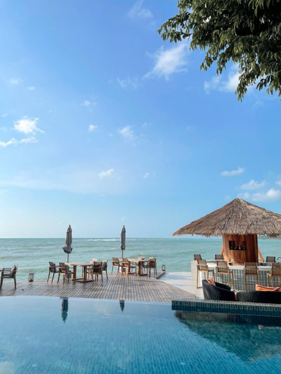 An infinity pool and a thatched beach sala beside the sea