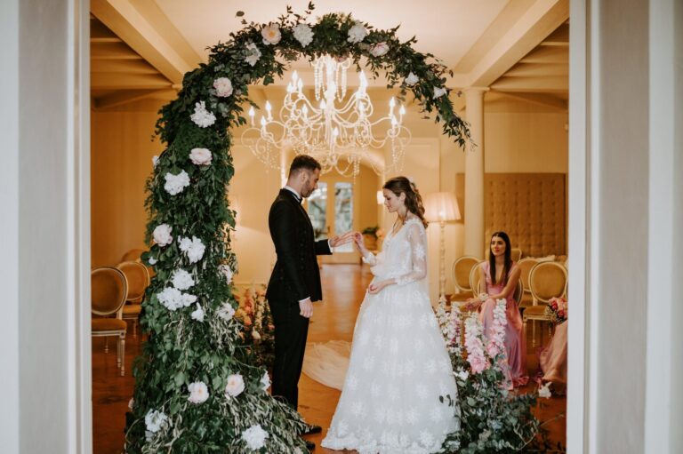 Indoor ceremony under a greenery and white-rose arch with a crystal chandelier, Villa di Ulignano, Tuscany (Sara & Marco), RoRas Destination Wedding