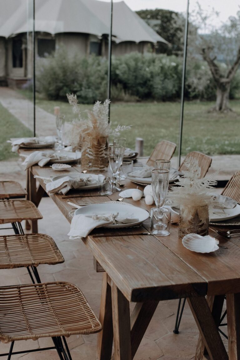 Long wooden tables laid for an outdoor dinner with dried flower arrangements, Terme di Vulci (Sara & Luca), RoRas Destination Wedding