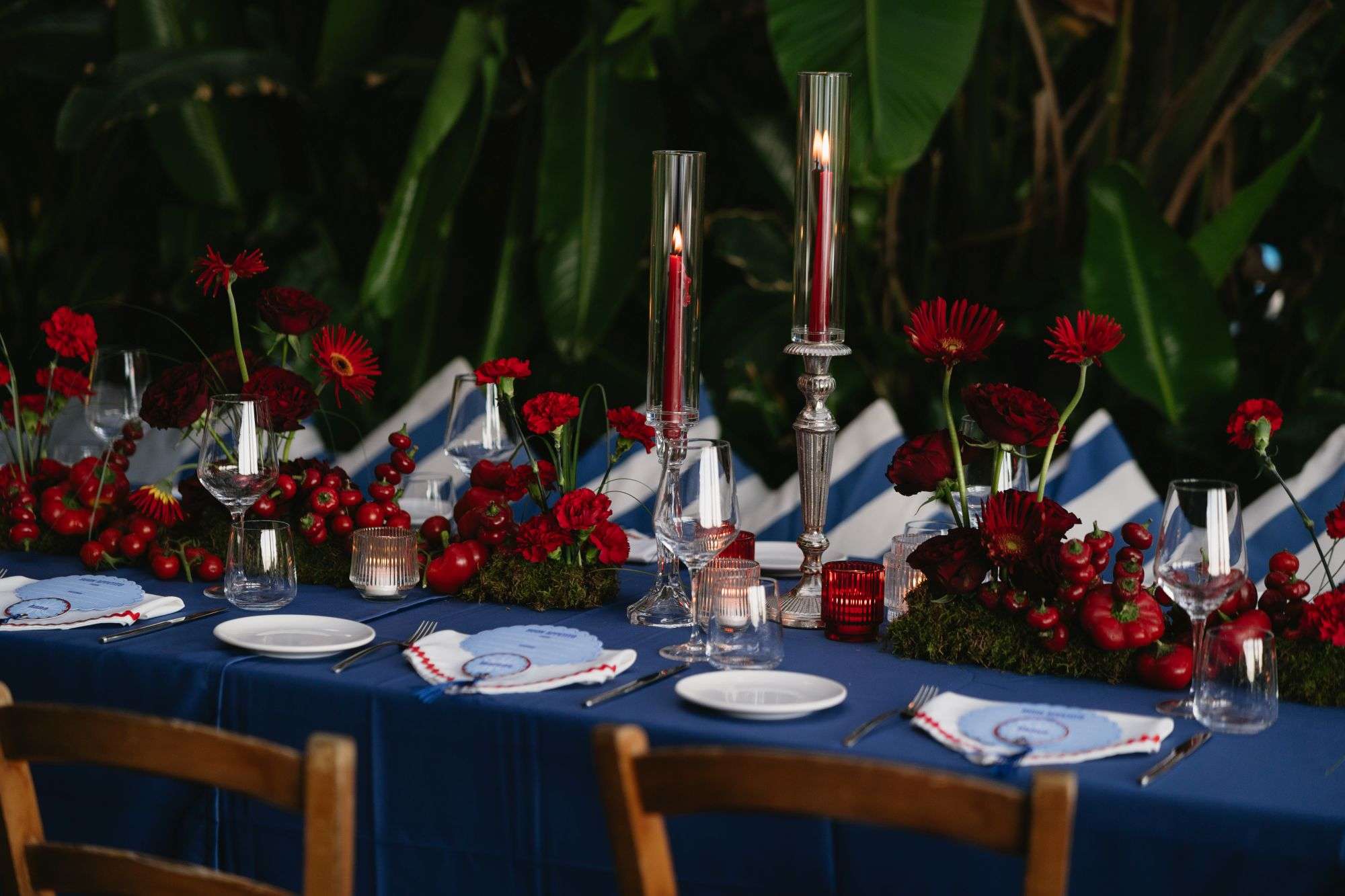 Dinner table in navy linen with red gerbera, carnations and tall red tapers among tropical leaves, Ischia (Lorna & Declan), RoRas Destination Wedding