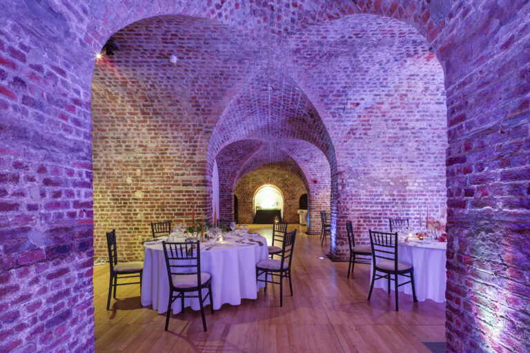 A round table set in a vault with coloured lighting, RSA House