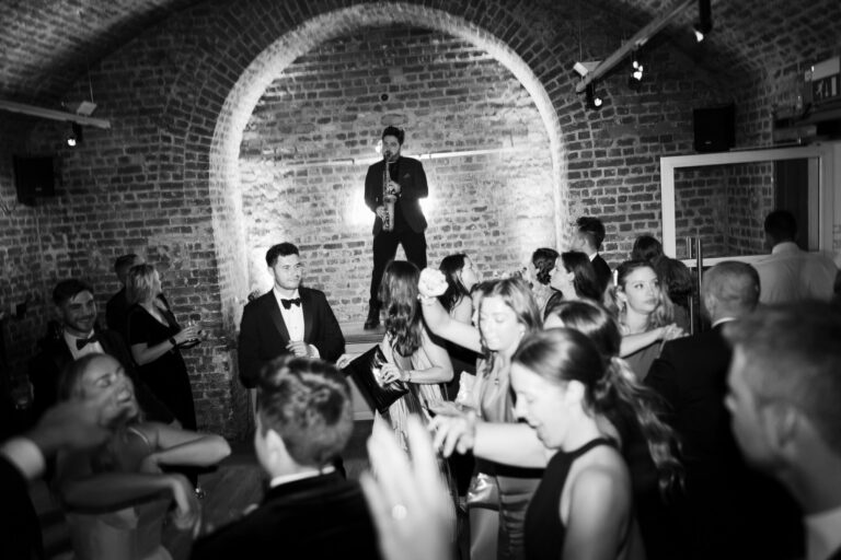 Guests gathered around a live performance beneath the brick arches, RSA House