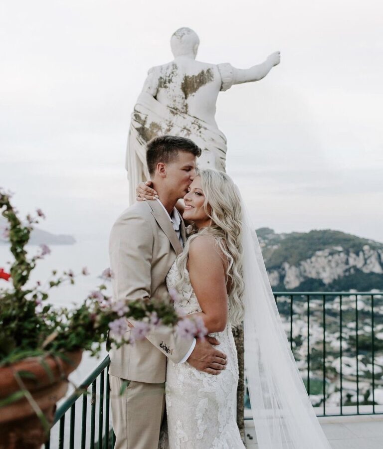 Couple embracing on a clifftop terrace by a classical statue, Samantha Pretto