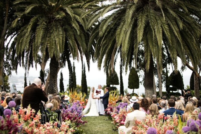 Outdoor ceremony on a clifftop lawn among palms and flowers, the sea beyond, Samuel Lippke Studios