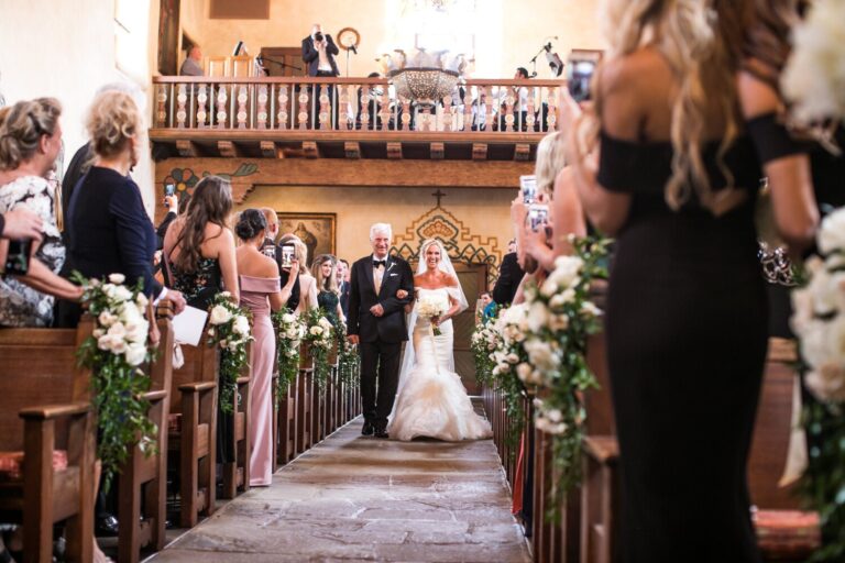 Bride walking the aisle of a church lined with guests and flowers, Samuel Lippke Studios