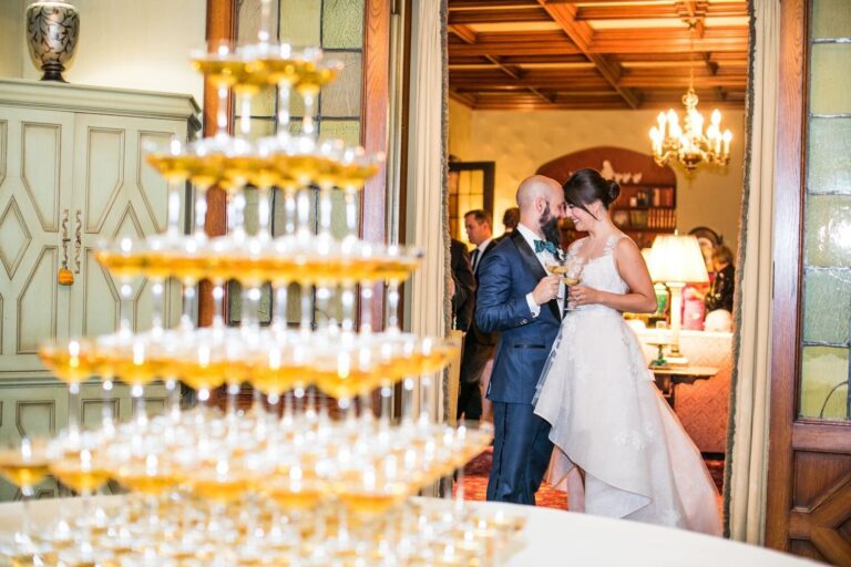 Couple beside a tall champagne tower in a panelled room, Samuel Lippke Studios