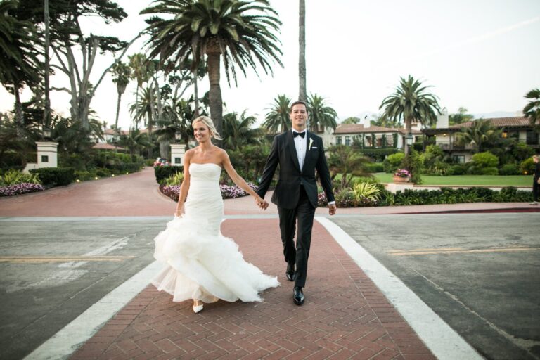 Bride and groom walking hand in hand along a palm-lined street, Samuel Lippke Studios
