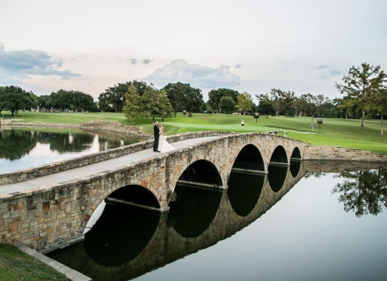 Distant couple by a stone bridge across a golf course lake, Samuel Lippke Studios
