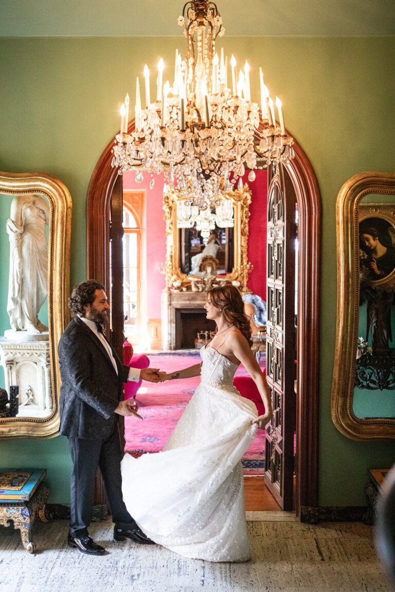 Bride and groom in a green panelled doorway beneath a crystal chandelier, Samuel Lippke Studios