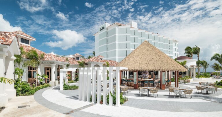 Resort buildings with a thatched bar and outdoor seating, Sandals Dunn's River