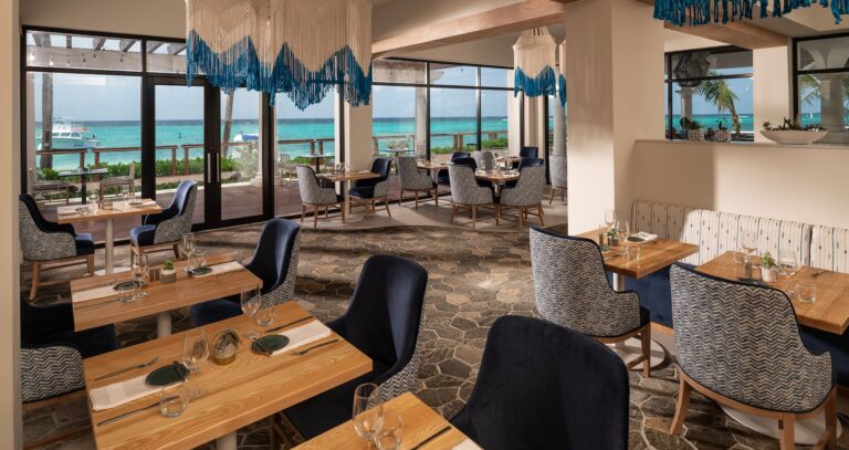 A restaurant with tables beside windows facing the sea, Sandals Dunn's River