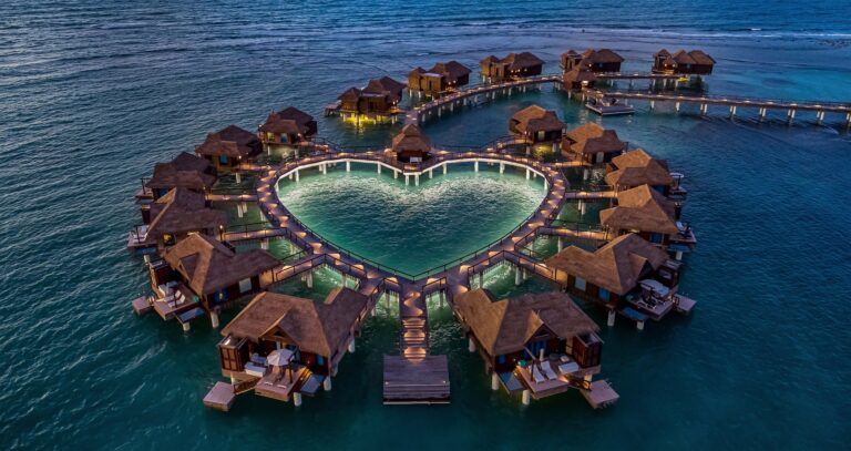 Overwater bungalows ringed around a heart-shaped lagoon, lit at night, Sandals Royal Caribbean Resort and Private Island