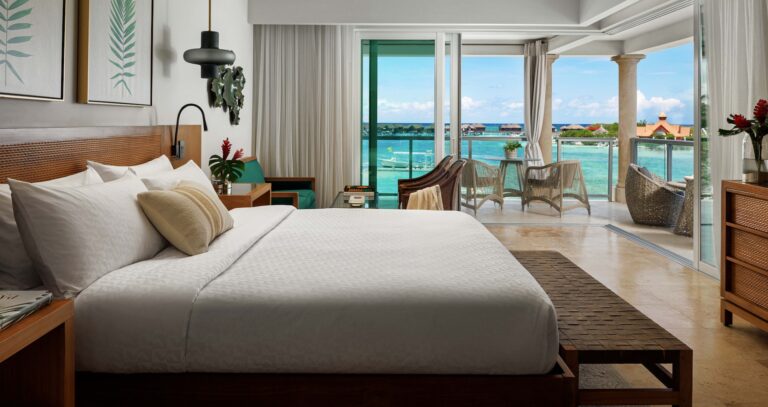 Suite bedroom opening to a balcony overlooking the lagoon and overwater bungalows, Sandals Royal Caribbean Resort and Private Island