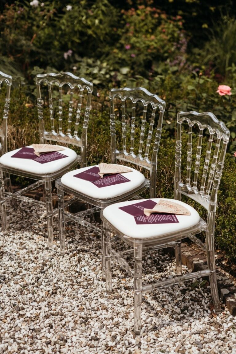 Clear acrylic chairs with programme cards for an outdoor ceremony, Sante Weddings