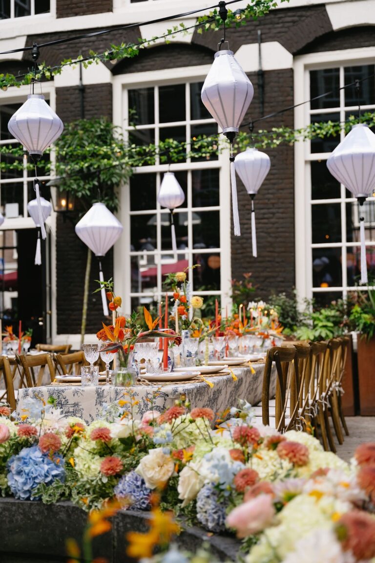 Reception table with paper lanterns and colourful flowers on a canal-house terrace, West-Indisch Huis, Amsterdam, Sante Weddings