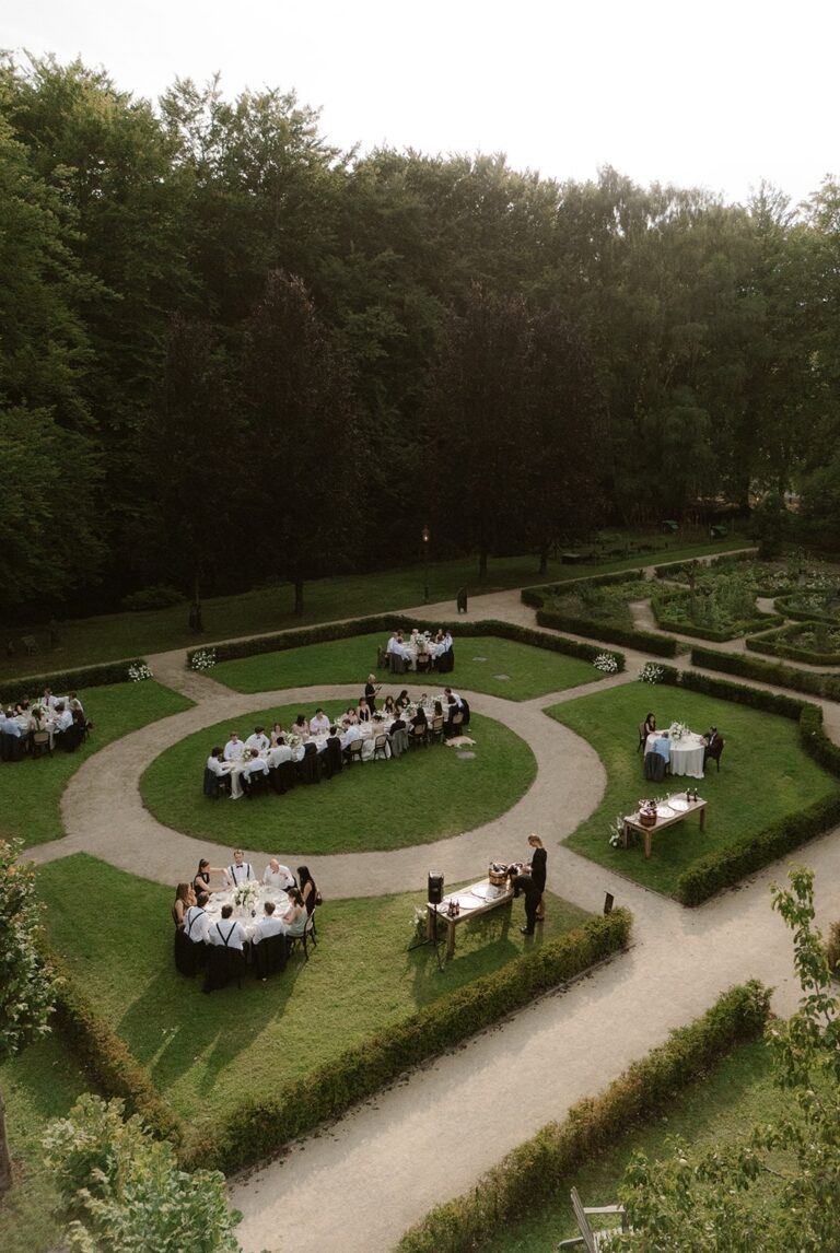 Round dining tables laid out in a formal castle garden, De Havixhorst, Sante Weddings