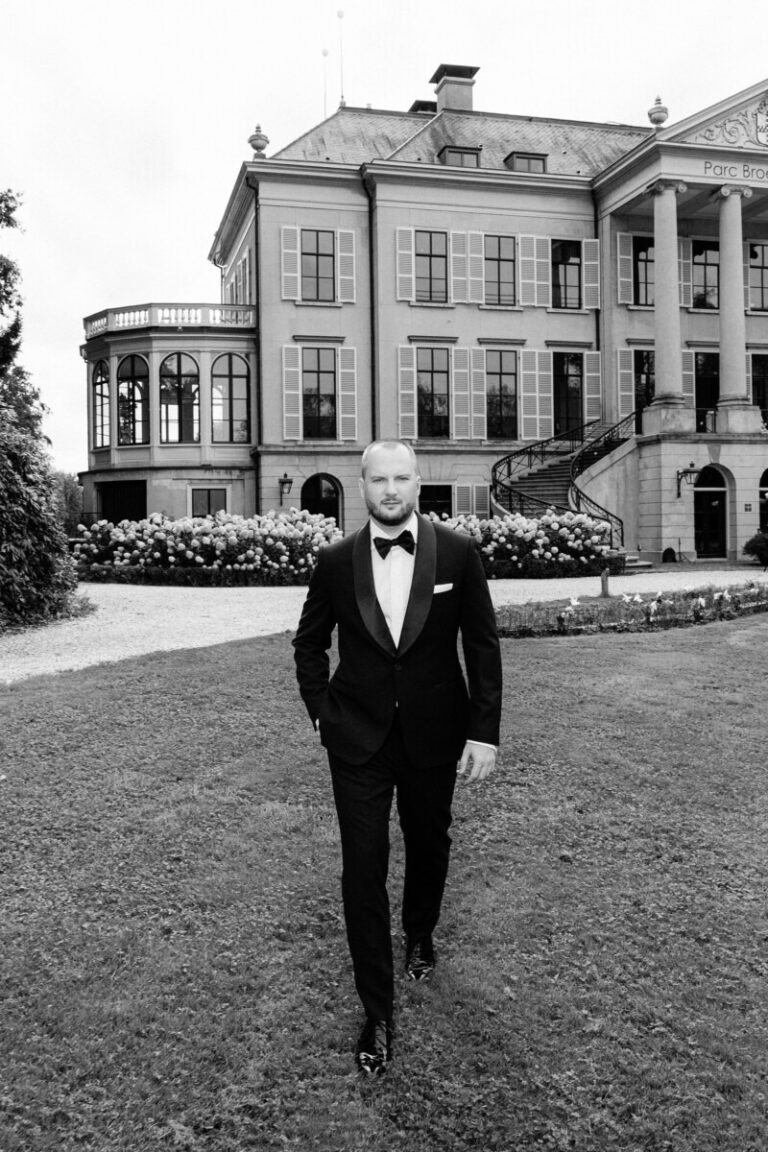 Groom walking across the lawn in front of a country house, Parc Broekhuizen, Sante Weddings