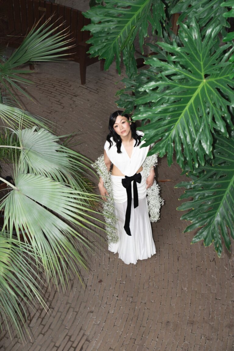 Bride in a white outfit with a black bow among palms, Hortus Botanicus, Amsterdam, Sante Weddings