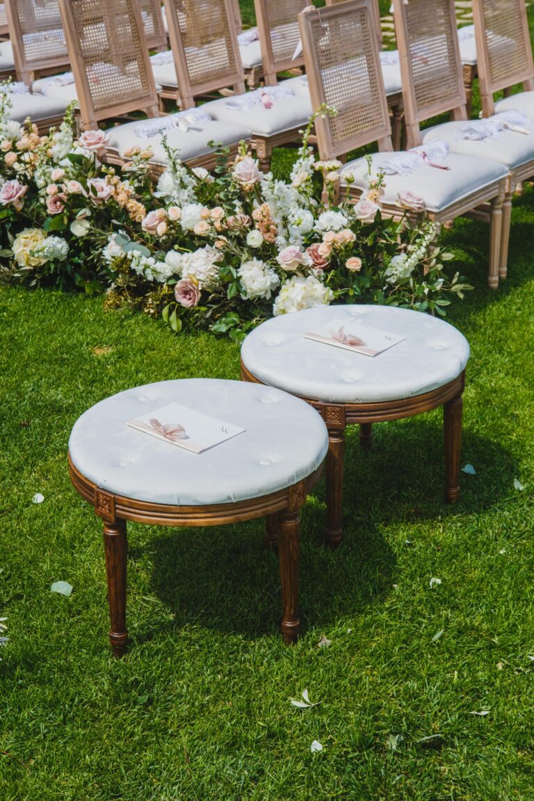 Round upholstered stools beside a rose-lined aisle on the ceremony lawn at Hotel Caruso, Ravello, Sara D'Angelo