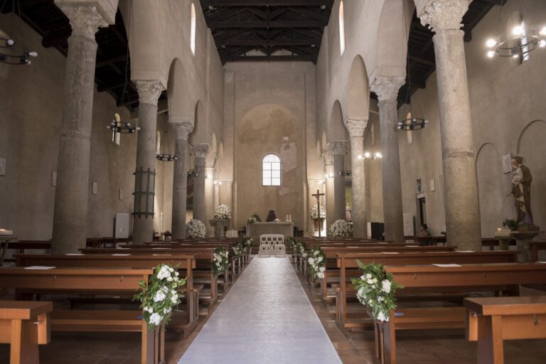 A church nave dressed with white flowers on the pews for a wedding ceremony, Sara D'Angelo