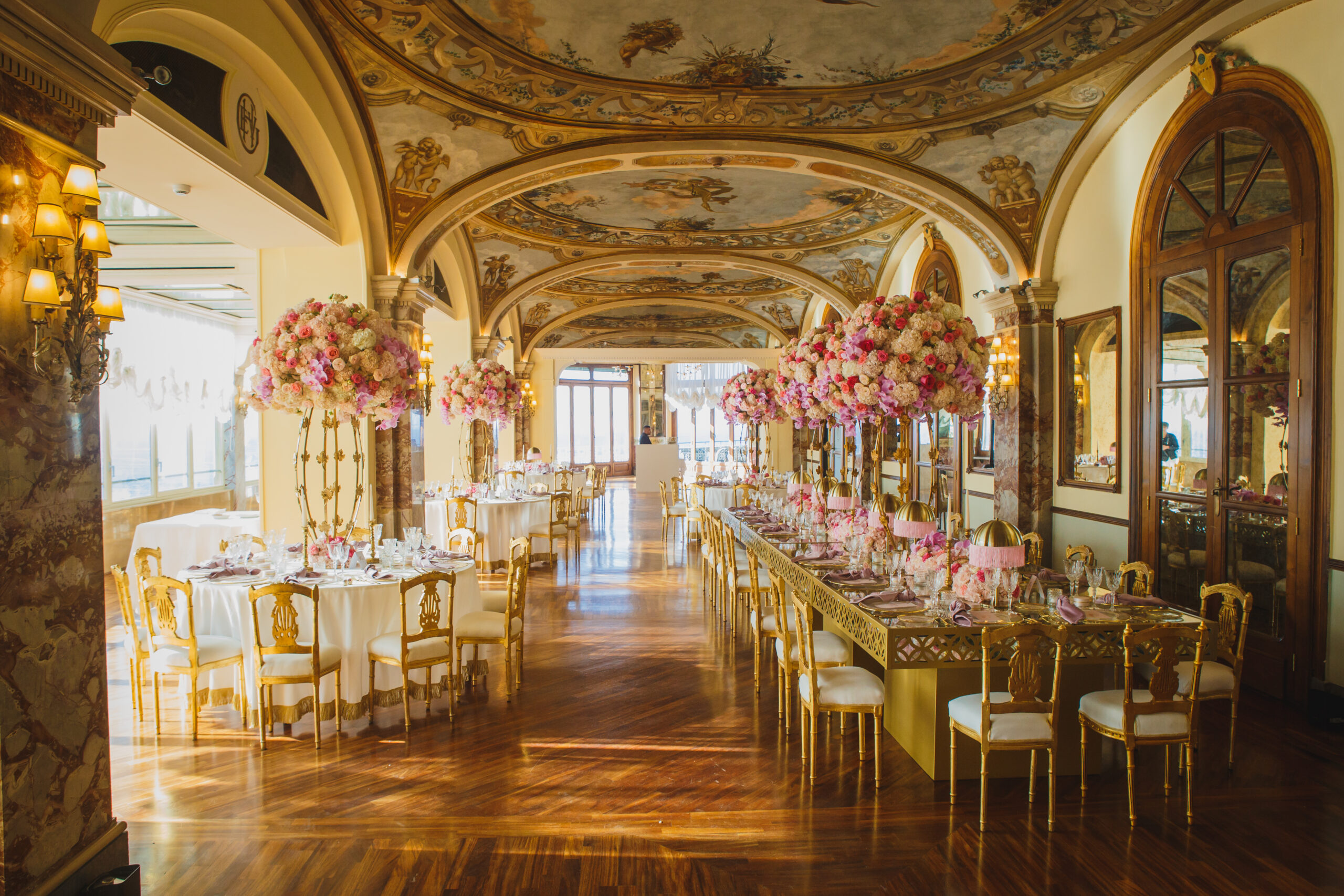 Dinner tables with tall pink and white centrepieces in a frescoed hall at the Excelsior Vittoria, Sorrento, Sara D'Angelo
