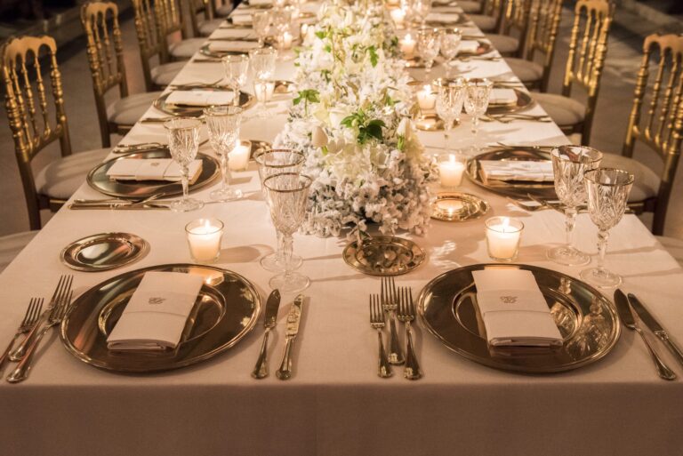 Long candlelit table with gold chargers and white flowers for a wedding at the Monastero di Santa Chiara, Naples, Sara D'Angelo