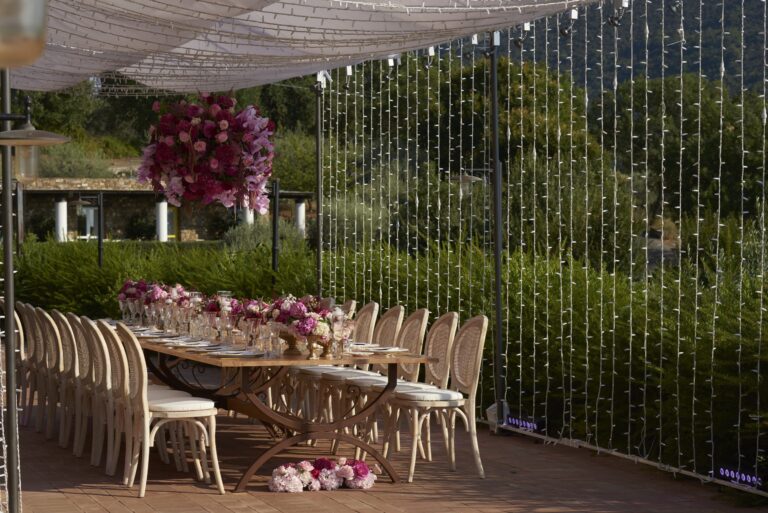 Table with pink and red flowers beside a curtain of lights at Villa la Pietraia, Sara D'Angelo