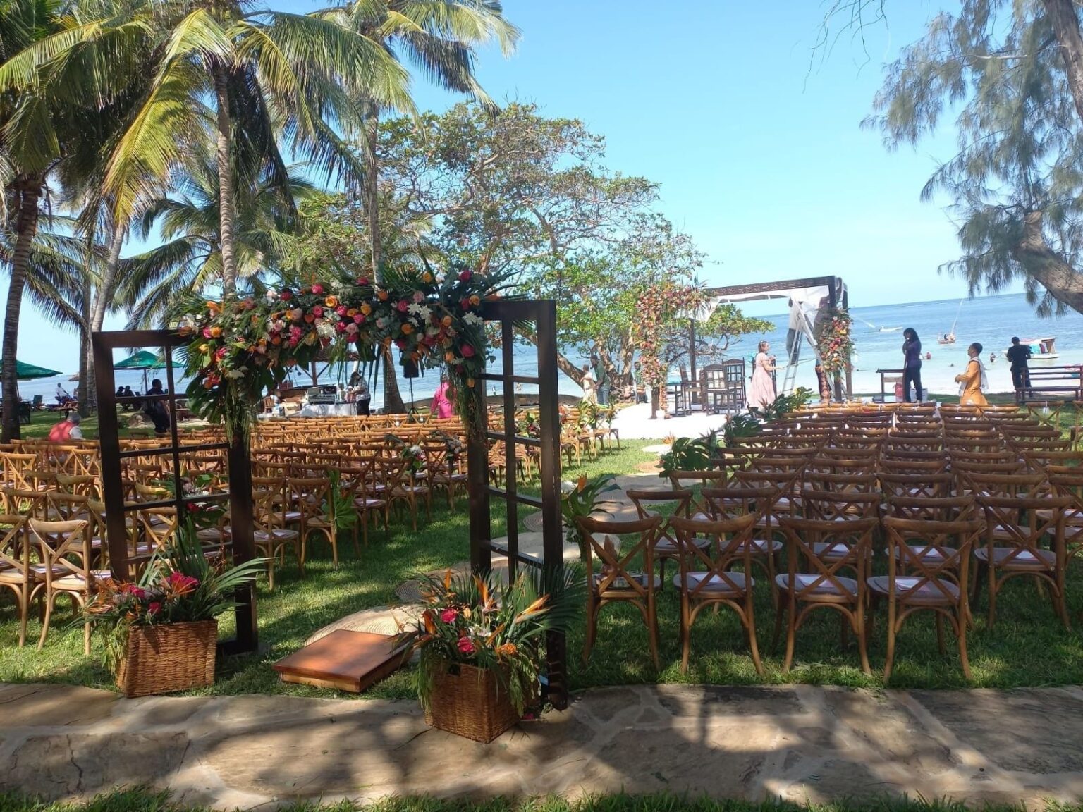 A floral ceremony arch and seating on the resort lawn by the sea