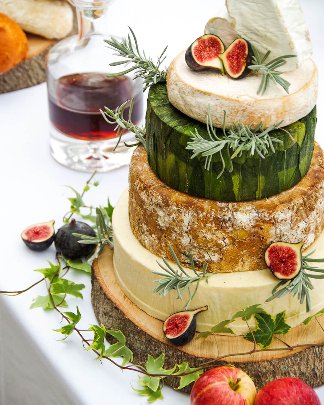 A tiered cheese wedding cake decorated with figs and rosemary