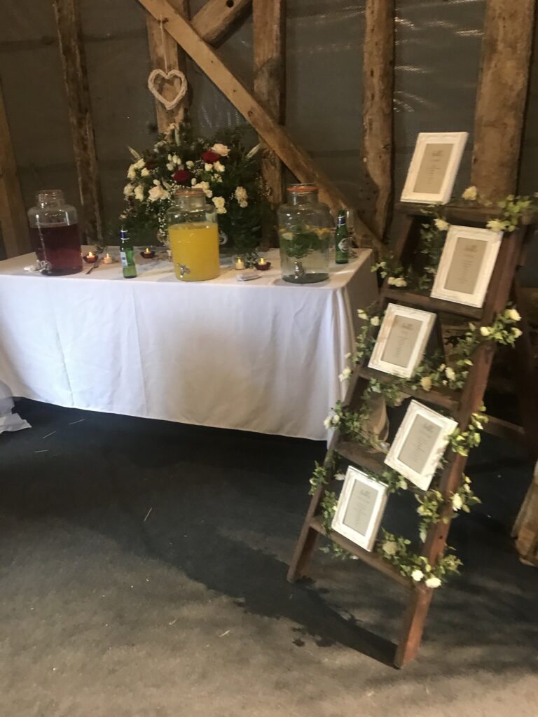 Barn wedding seating plan on a ladder with flowers, Serendipity Street