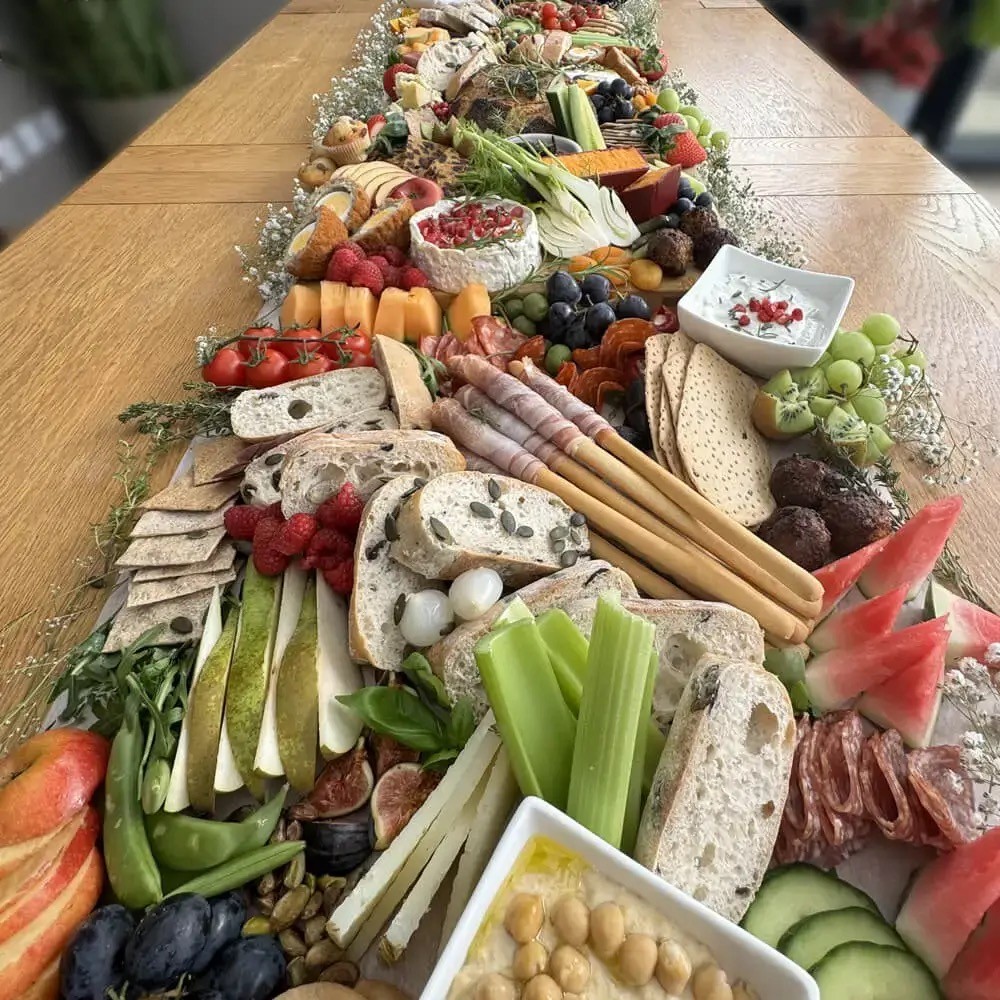 A long grazing table with cheeses, cured meats, fruit and bread