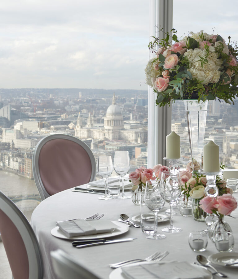 A table laid with crystal and pink roses, St Paul's Cathedral in the window behind, Shangri-La Hotel, The Shard, London