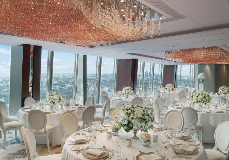 The Ren Room set for a wedding dinner with round tables, white chairs and white flowers under the chandeliers, Shangri-La Hotel, The Shard, London