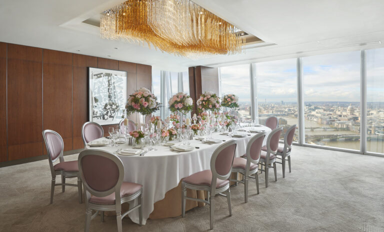 A long wedding table with pink upholstered chairs and roses in a private room overlooking the river, Shangri-La Hotel, The Shard, London