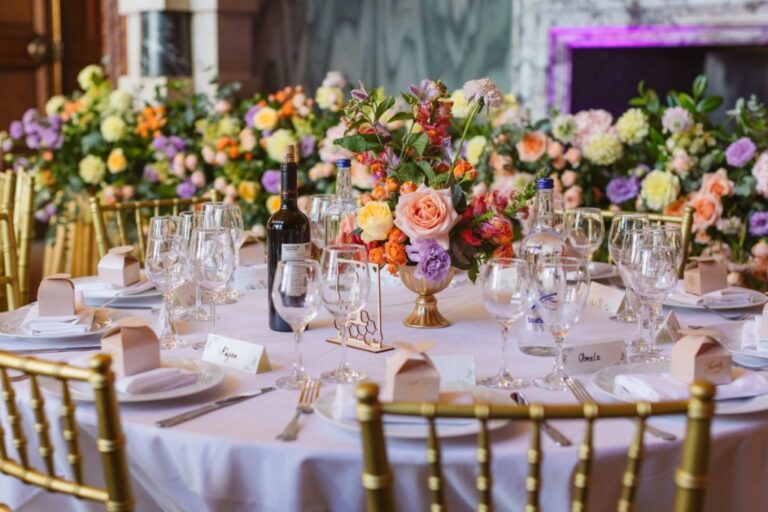 Pastel centrepieces dress round tables beneath a grand chandelier, Shilpa Reddy