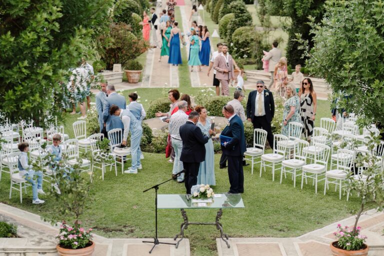 The ceremony down a clipped garden path, guests in white chairs on both sides, Sicilian Wedding Day