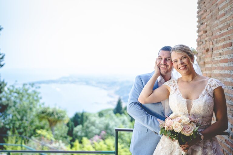 The couple on a terrace above the bay, the coast running north behind them, Sicilian Wedding Day