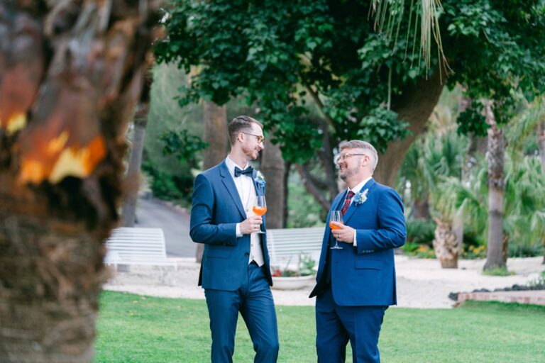 Two grooms with drinks under an old tree, candles burning in the foreground, Sicilian Wedding Day