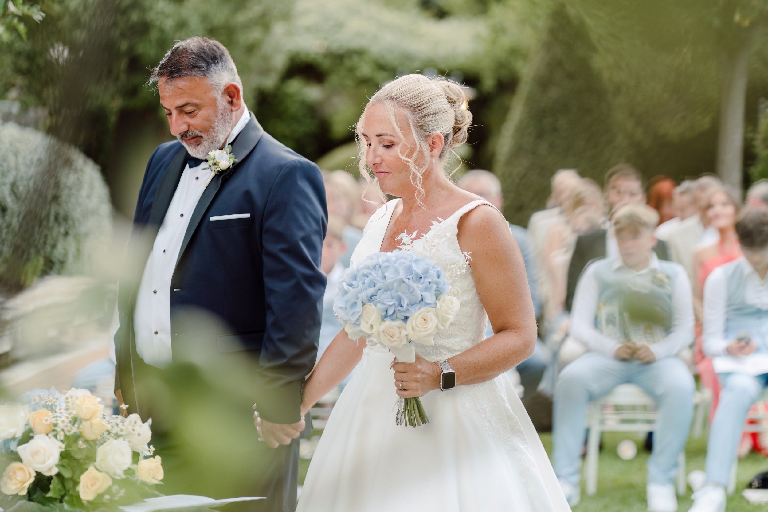 The bride on her father's arm, blue and white hydrangea in her hands, Sicilian Wedding Day