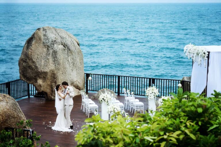 Ceremony on a timber deck beside a granite boulder above the sea, Silavadee Pool Spa Resort