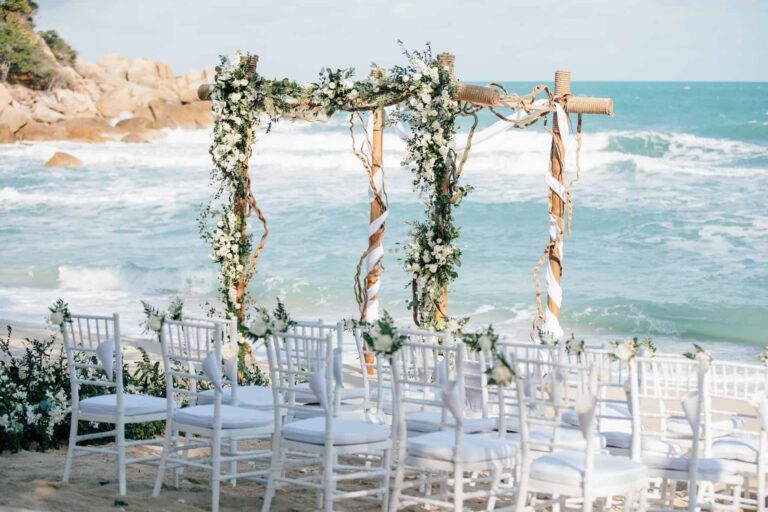 Floral arch and white chairs on the sand at the water's edge, Silavadee Pool Spa Resort