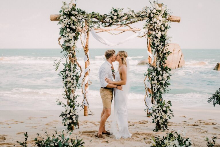 Couple embracing beneath a floral arch on the beach, Silavadee Pool Spa Resort