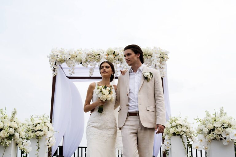 Couple walking back along the deck after the ceremony, flowers lining the railing, Silavadee Pool Spa Resort