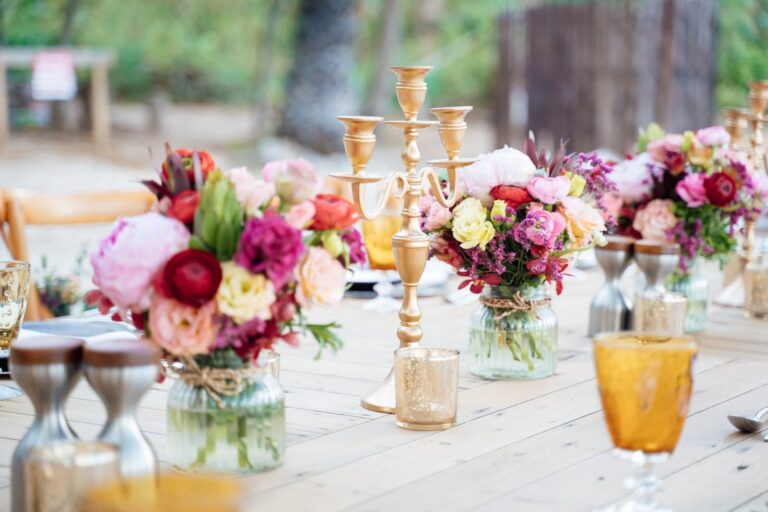 Long banquet table with bright flower arrangements on a timber deck, Silavadee Pool Spa Resort