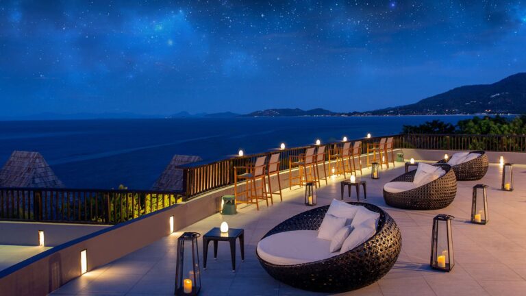 Terrace lounge seating and lanterns above the coast at night, Silavadee Pool Spa Resort